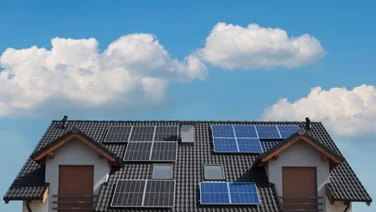monocrystalline and polycrystalline solar panels on a house against a blue sky with clouds