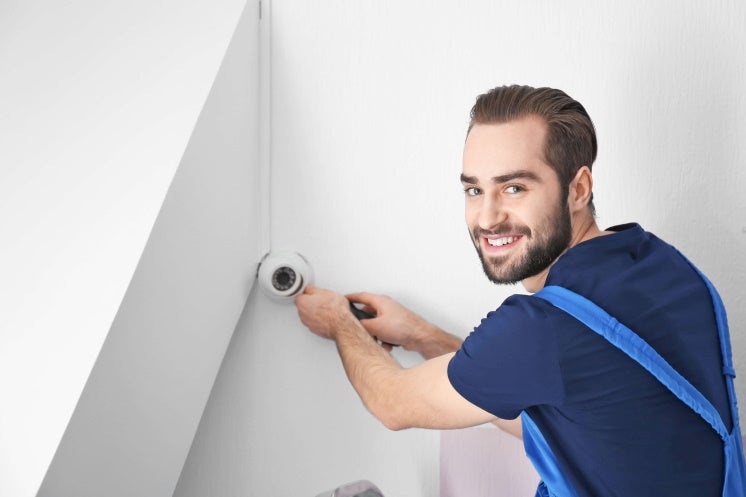 man installs a home security alarm