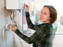 a woman adjusts her combi boiler