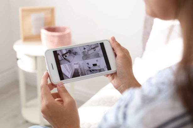 a woman looks at her phone to check what her smart security home cameras are seeing