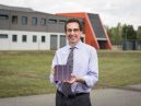 Dr Chris Case outside Oxford PV's German factory, holding a perovskite tandem solar cell
