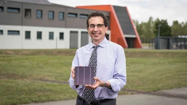 Dr Chris Case outside Oxford PV's German factory, holding a perovskite tandem solar cell