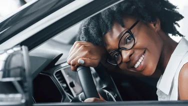 woman resting head on wheel of new car