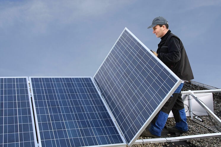 Installers fitting solar panels on flat roof