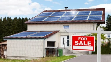 solar panels on a home with a for sale sign