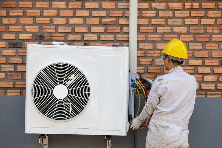 Someone performing heat pump installation outside