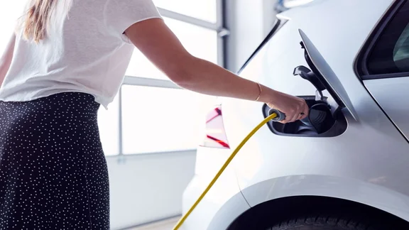 woman plugging charger into electric vehicle