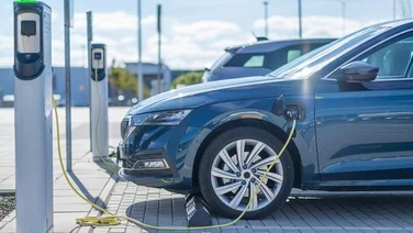 Cars lined up charging at electric vehicle charging points on a sunny day