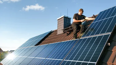 Man installing solar panels on a roof