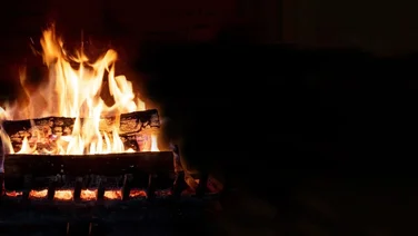 Log burner burning wood, against a black background