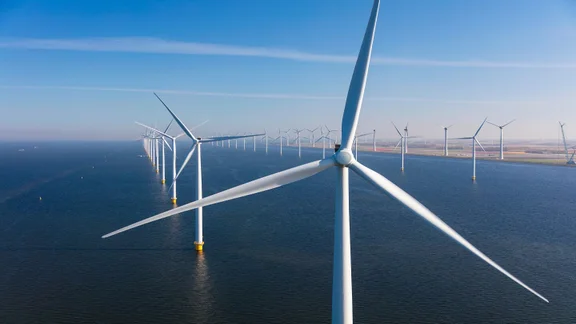 Close up of an offshore wind turbine with other turbines in the distance