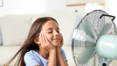 girl in a home smiling in a fan's breeze