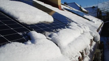 Solar panels covered by snow on the home roof on a sunny winter's day