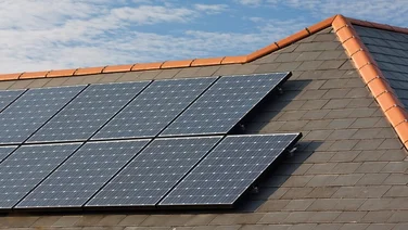 Solar panels on a slate roof under a blue sky