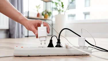 man's hand putting plug into an outlet extension