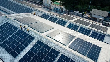 Engineers set up solar panels on the roof of a factory