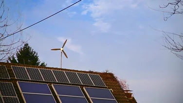 House with solar panels and wind turbine.