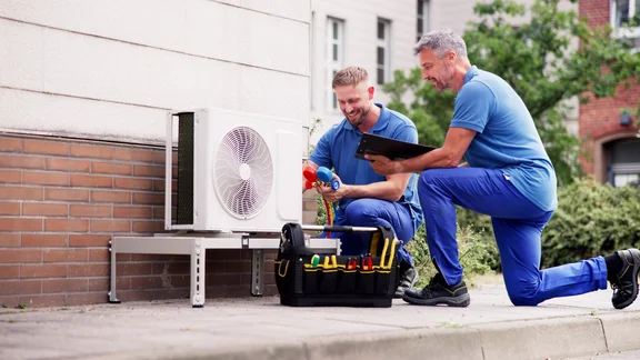 Two men fixing a heat pump