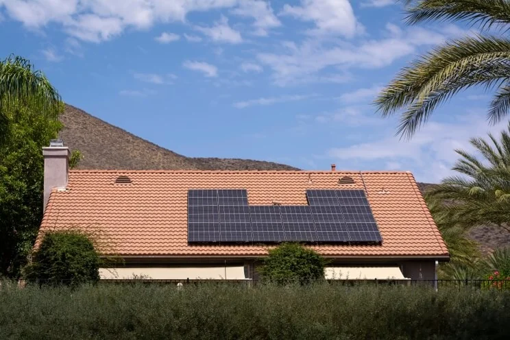 solar panels on a roof against a blue sky and palm trees