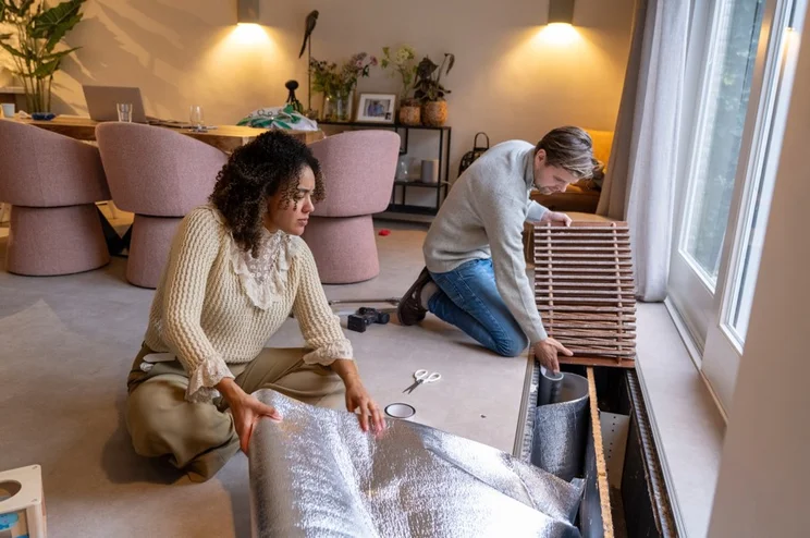 A couple installing insulation in their home.
